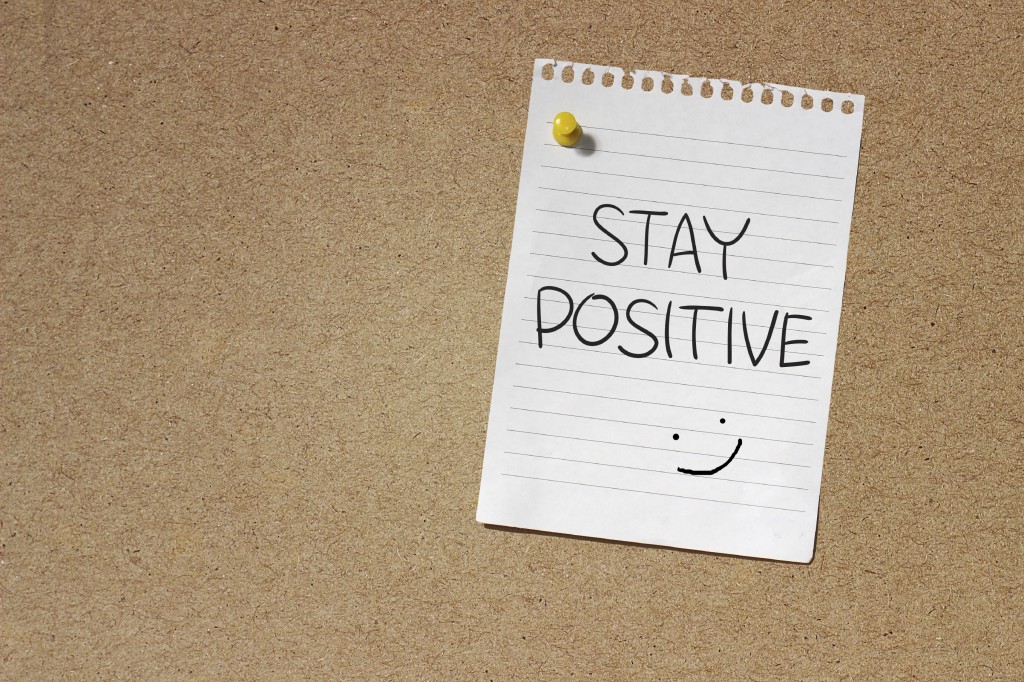 Motivational Concept Image of message note paper pinned on cork board with Stay Positive words written on it